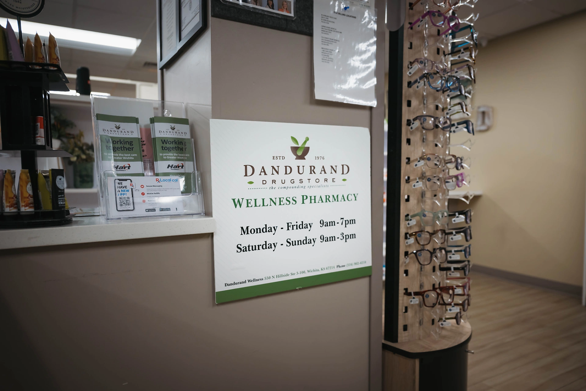 Dandurand Wellness Pharmacy counter and hours sign at Wesley Medical Center in Wichita, KS