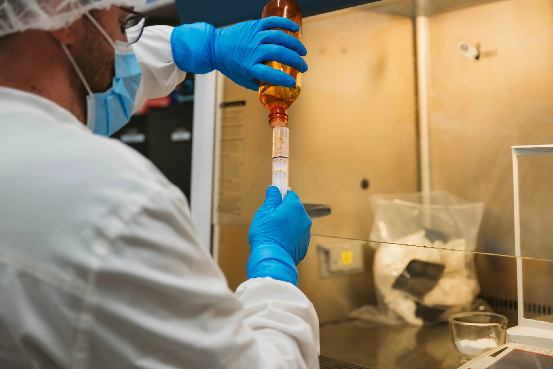 Dandurand Drugstore pharmacist drawing a compounded liquid into a syringe inside the cleanroom hood