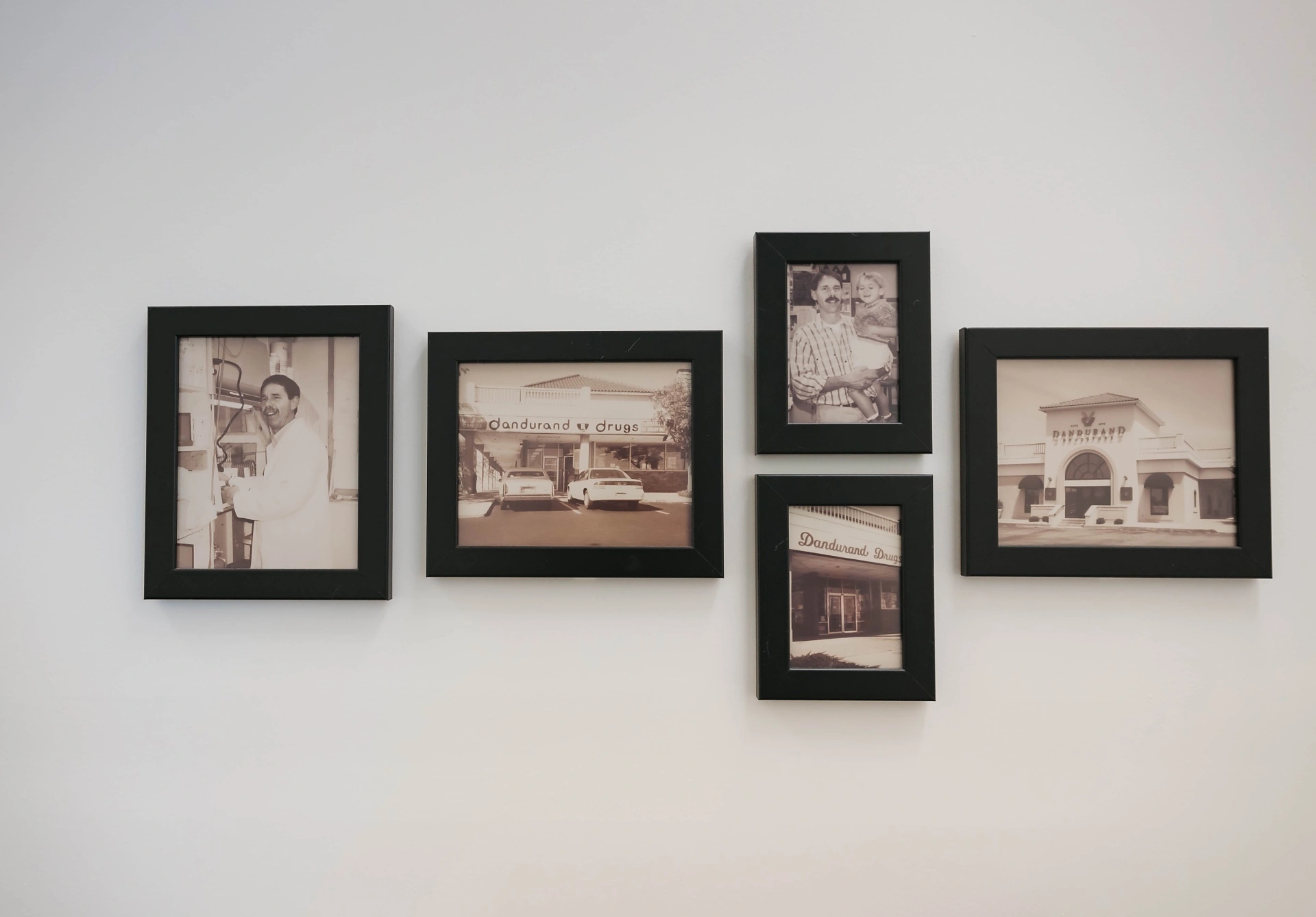 Framed historical photographs of Dandurand Drugstore storefronts and pharmacists from 1976 onward, on display in Wichita, KS
